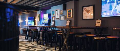 A bar area with stools, a counter, and a television screen displaying a sports event.