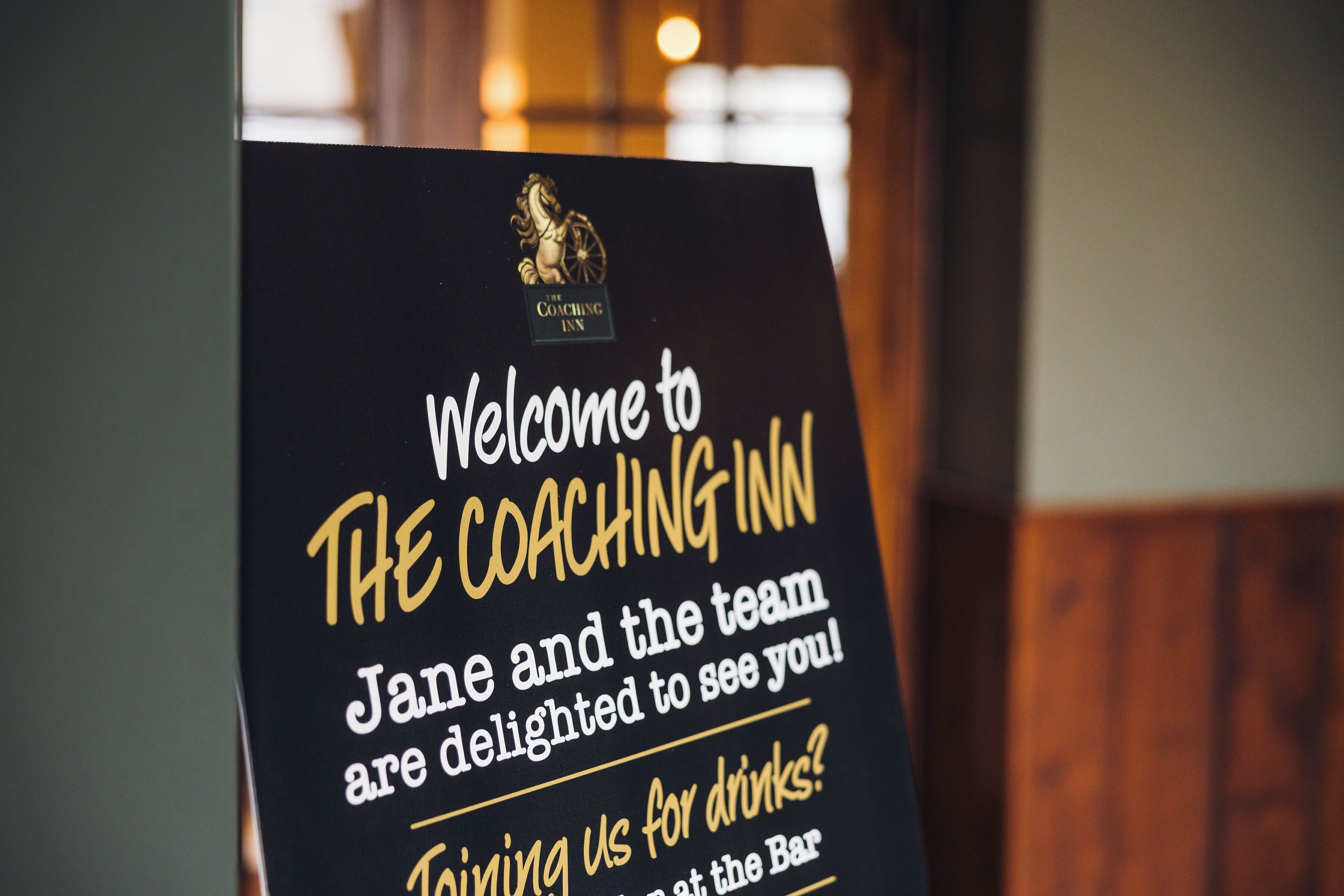 A welcome sign for The Coaching Inn with text inviting guests and mentioning a person named Jane.