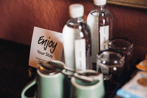 A table with a sign that reads 'Enjoy Your Stay,' a spoon, and two bottles. - Coaching Inn (South Molton)