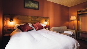 A hotel room with a large bed, a wooden headboard, two bedside lamps, a sofa, and a painting on the wall. - Coaching Inn (South Molton)