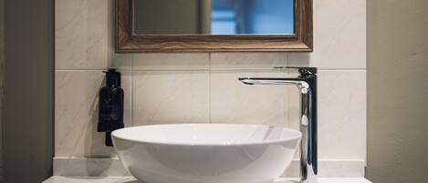 A bathroom with a white marble sink, a wooden-framed mirror, and a towel hanging on the wall.