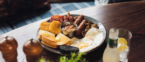 A breakfast plate with eggs, sausages, beans, and toast on a wooden table.