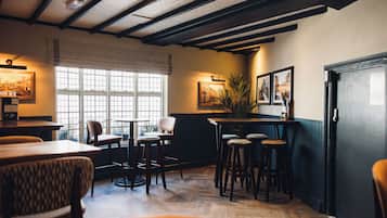 A cozy restaurant interior with wooden floors, bar stools, and framed pictures on the walls.