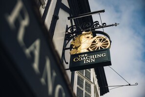 A sign for The Coaching Inn with a horse and wheel design. - Coaching Inn (South Molton)