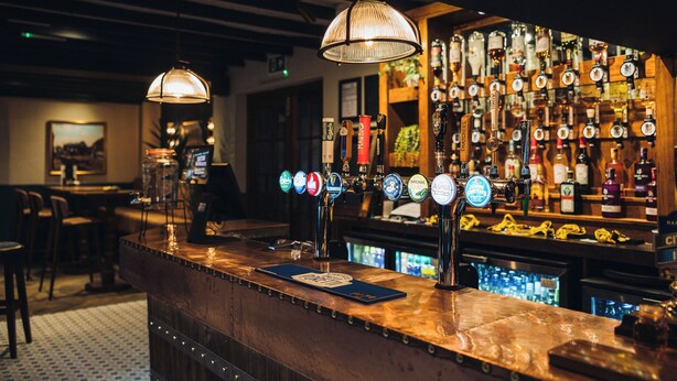 A bar area with multiple beer taps and a variety of liquor bottles. - Coaching Inn (South Molton)