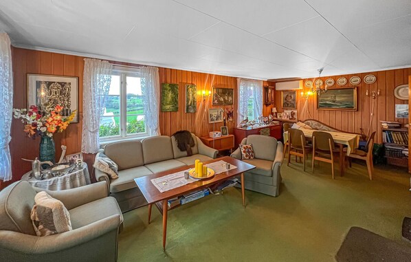 Una sala de estar acogedora con sofá, sillas, una mesa de comedor y una zona de cocina.