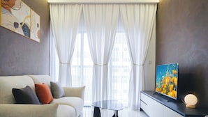 Een moderne woonkamer met een bank, een salontafel, een flatscreen-tv en decoratieve verlichting.