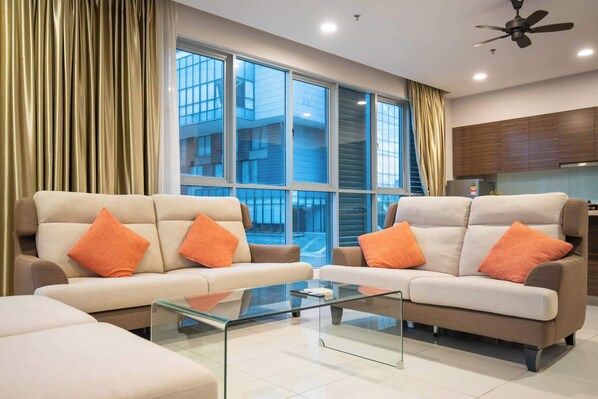 A modern living room with two sofas, a glass coffee table, and large windows with curtains.