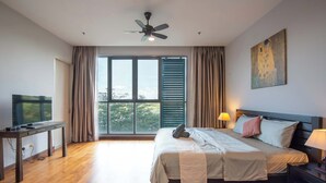 Habitación de hotel moderna con una cama grande, un escritorio, un ventilador de techo y vistas a árboles a través de la ventana.