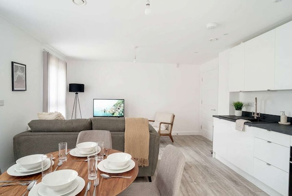 A modern living space with a dining area, sofa, and kitchen.