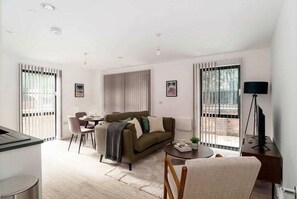 A modern living room with a sofa, a dining table, and a TV stand.
