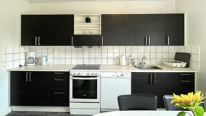 Une cuisine moderne avec des meubles de couleur noire, un plan de travail blanc, une cuisinière, un four et un évier.