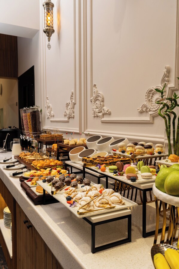 A buffet with various food items, a decorative wall, and a tall plant. - Marhaba Hotel & Spa (Tashkent)