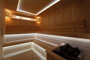 Sauna, jossa on puiset lauteet ja näkyvissä oleva puukiuas.