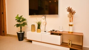 Una sala de estar moderna con un televisor de pantalla plana montado en la pared, un mueble blanco de entretenimiento debajo y plantas decorativas.