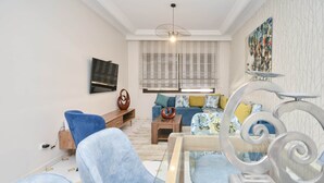 A modern living room with a sofa, blue armchairs, a coffee table, and a decorative metal sculpture. - Cozy 2 BR Gauthier Oasis (Casablanca)