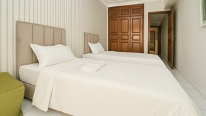 A bedroom with two beds, a green armchair, and a wooden wardrobe. - Cozy 2 BR Gauthier Oasis (Casablanca)