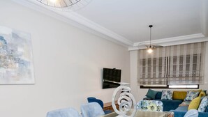 A dining area with a glass-top table, blue upholstered chairs, and a floral-patterned chair. - Cozy 2 BR Gauthier Oasis (Casablanca)