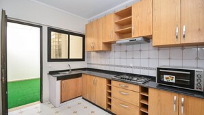A kitchen with wooden cabinets, a gas stove, a microwave, and a window with a view of a green lawn. - Cozy 2 BR Gauthier Oasis (Casablanca)