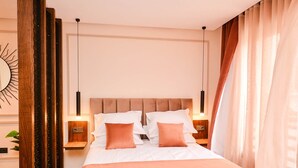 A modern bedroom with a large bed, wooden headboard, bedside tables, and a hanging light fixture.