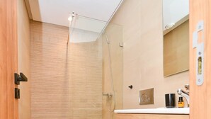 A modern bathroom with a glass shower enclosure, a wooden vanity, and a toilet.