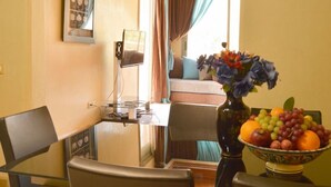 A dining area with a glass table, chairs, a vase with flowers, and a fruit bowl. - Palmeraie Stay - Pool & Lake (Marrakesh)