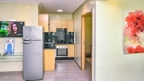 Une cuisine moderne dotée d’appareils électroménagers en acier inoxydable, de meubles en bois et d’un sol carrelé.