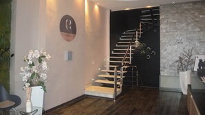Un intérieur moderne avec un escalier, un logo sur le mur et un vase rempli de fleurs.