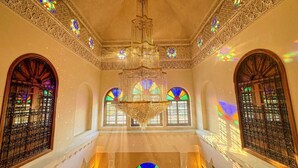 An ornate interior with a chandelier, stained glass windows, and intricate wall designs. - Charming Luxury Villa | Pool & Hot Tub (Marrakesh)