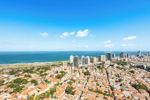 A coastal cityscape with dense urban buildings, a clear blue sky, and a view of the sea. - High-Rise Sea-View Stay by Sea N' Rent (Tel Aviv)