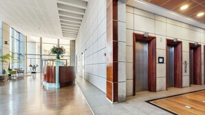 A modern lobby with a reception desk, elevators, and a spacious area with a wooden floor and large windows. - High-Rise Sea-View Stay by Sea N' Rent (Tel Aviv)