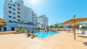 A swimming pool area with a clear sky, a building with balconies, and a mural on the wall. - Cobalt Canvas Residence, by OYOOSTAYS (Mil Palmeras)