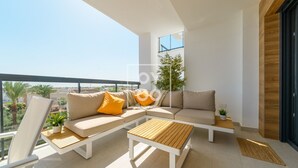 A modern balcony with a sofa, two wooden tables, and a potted plant. - Cobalt Canvas Residence, by OYOOSTAYS (Mil Palmeras)