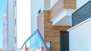 A modern staircase with glass railings leading to a wooden and white building facade. - Cobalt Canvas Residence, by OYOOSTAYS (Mil Palmeras)