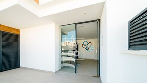 A modern building entrance with a glass door, a visible interior with a sofa and a wall-mounted artwork, and a wooden floor. - Cobalt Canvas Residence, by OYOOSTAYS (Mil Palmeras)