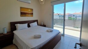 Una camera da letto moderna con un letto grande, un comodino, un condizionatore d'aria a parete e vista sul balcone esterno.