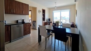 Una cucina moderna con lavastoviglie, lavatrice e zona pranzo con tavolo e sedie.