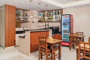 A bar area with a wooden bar counter, seating, and a Coca-Cola refrigerator. - Marlo Hotels  (Kathmandu)