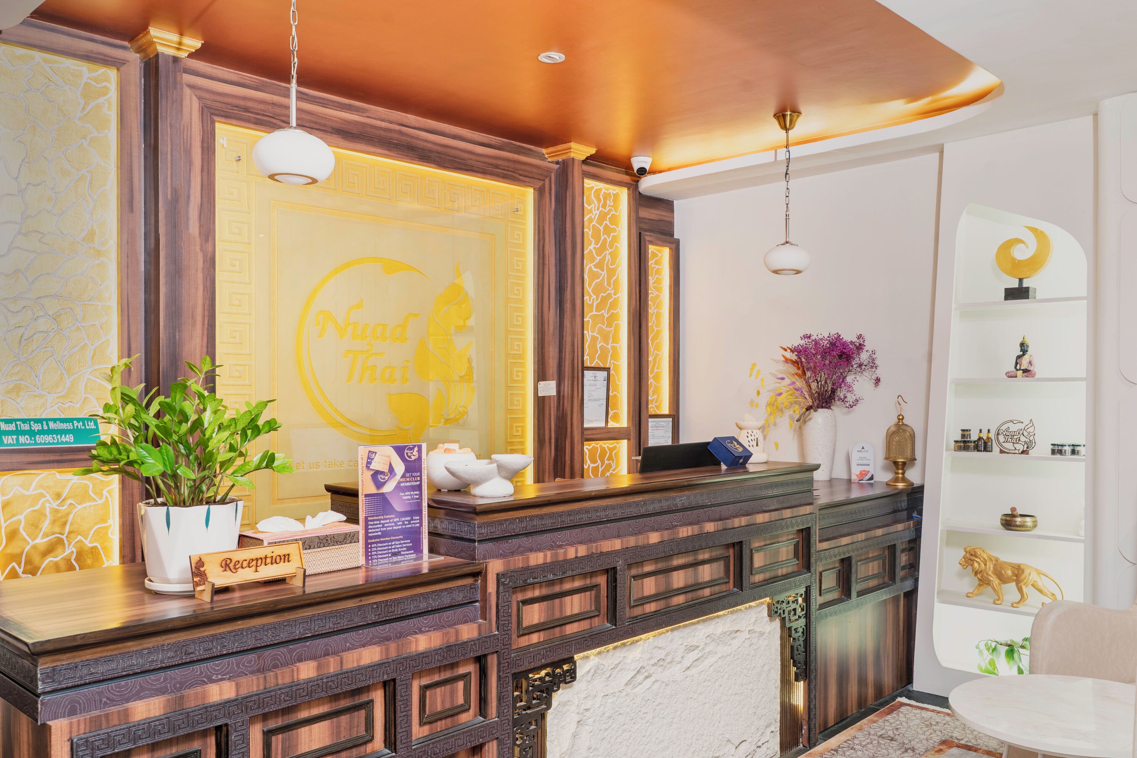A reception desk with a sign reading 'Nud Thai Spa & Wellness Pvt. Ltd.' and a reception area with a potted plant, a sign for membership, and a decorative shelf with items.