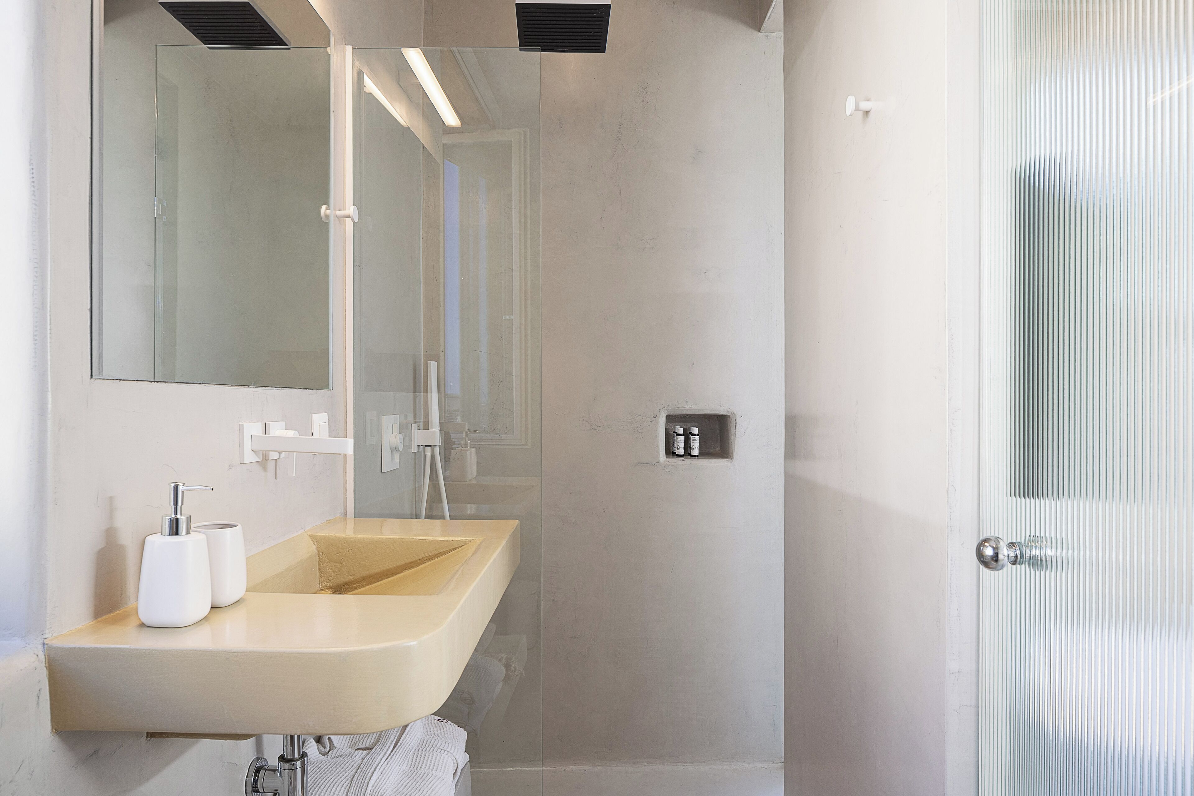 Une salle de bain moderne avec un lavabo beige, un grand miroir et une douche à parois de verre.