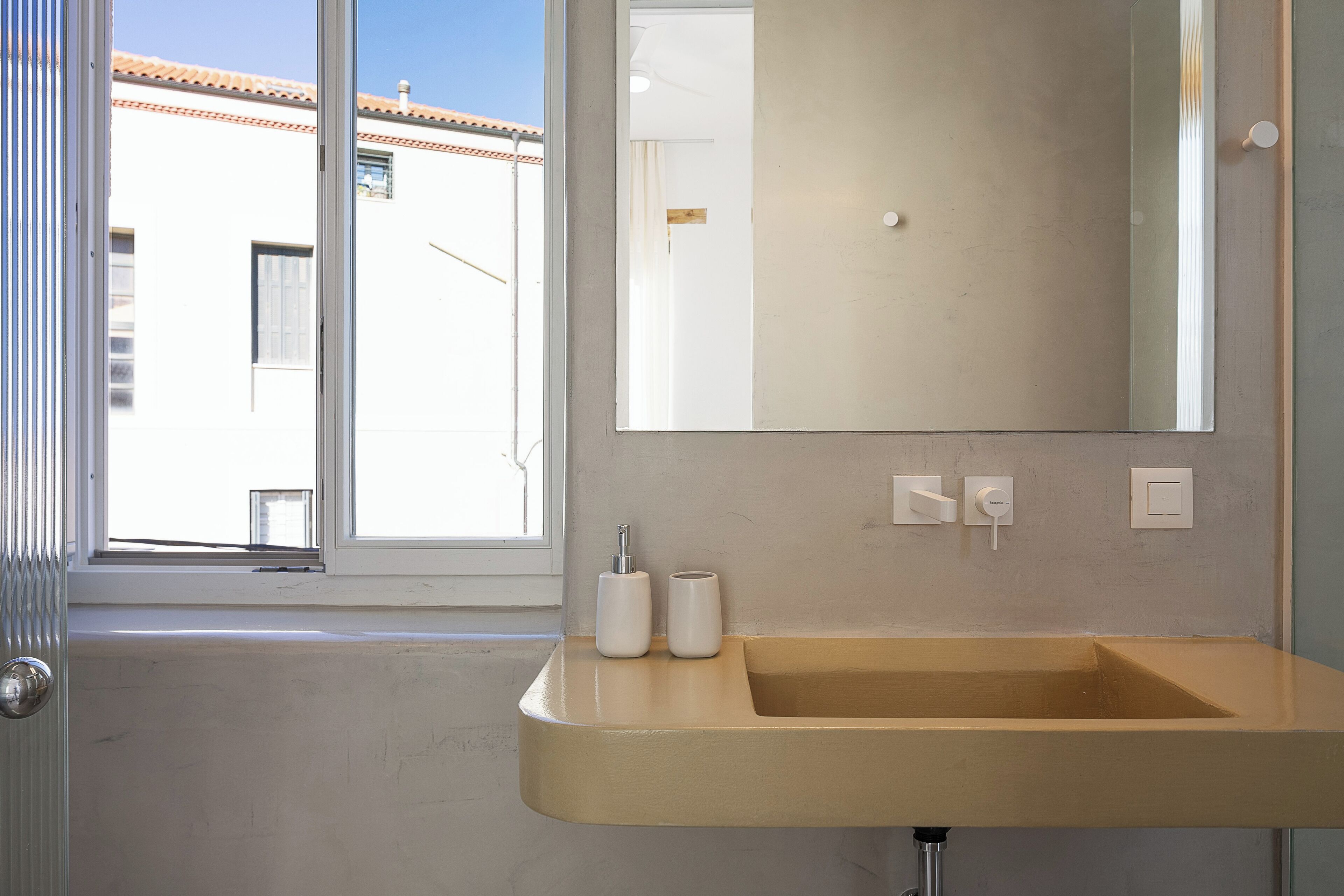 A bathroom with a beige sink, a large mirror, and two white bottles on the counter.