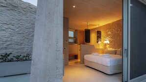 Un dormitorio moderno con una cama grande, un baño con bañera y vistas al exterior.
