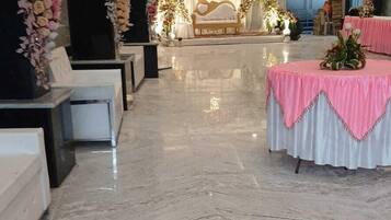 A spacious hall with a central stage, seating arrangements, and a marble floor.