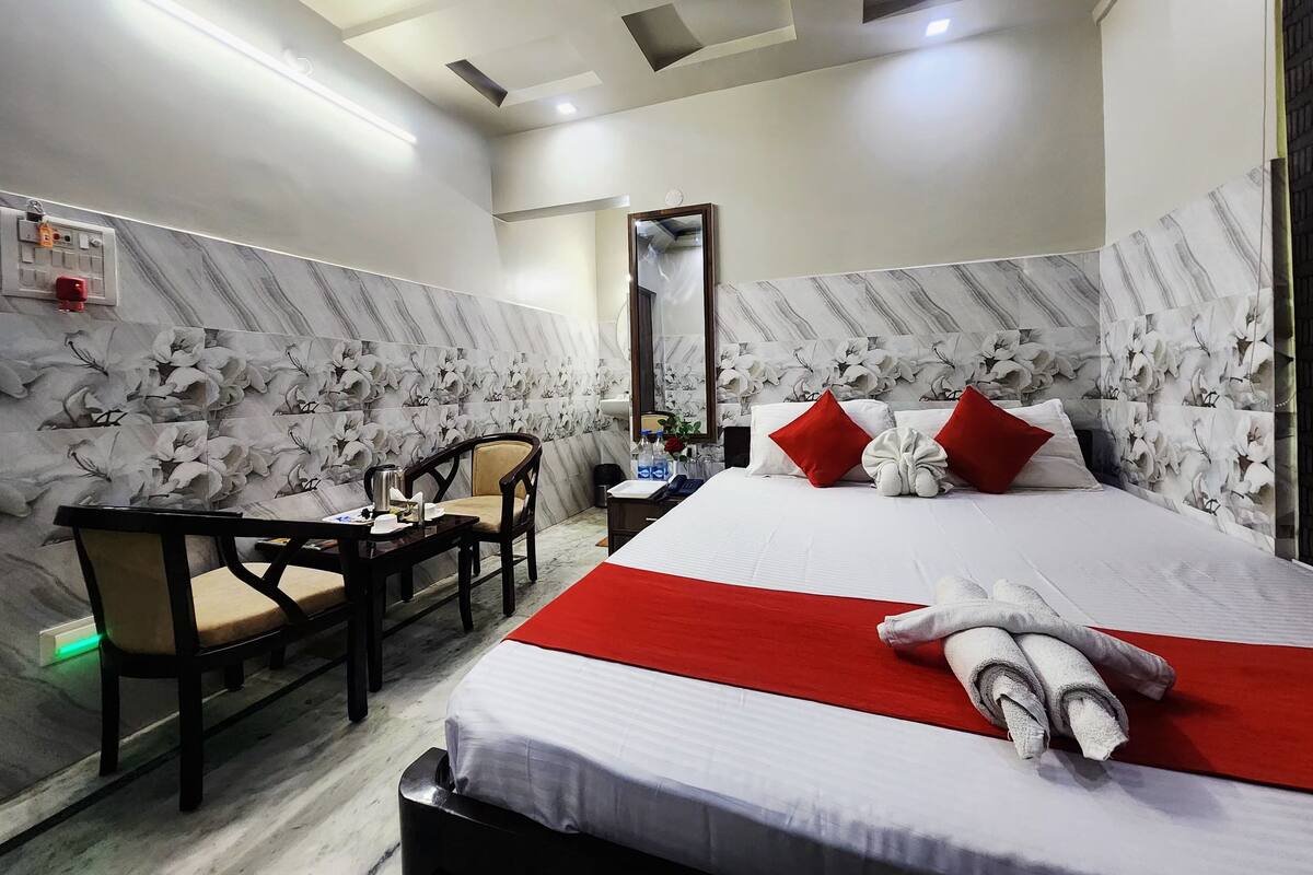 A hotel room with a bed, a desk, a chair, and a mirror.