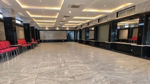 A spacious lobby with a marble floor, red chairs, and a reception desk. - Anandaloke Residency (Kolkata)