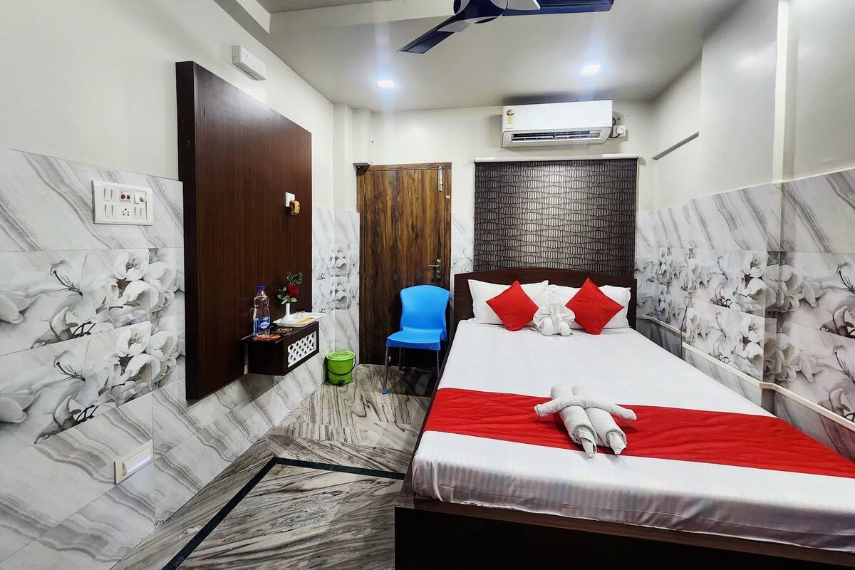 A hotel room with a bed, a chair, a desk, and a ceiling fan.