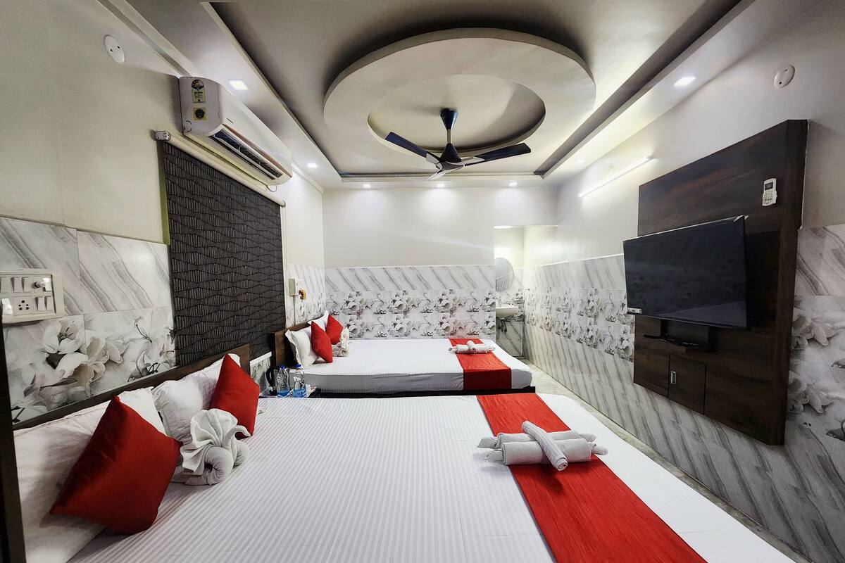 A hotel room with two beds, a TV, a ceiling fan, and marble-patterned walls.