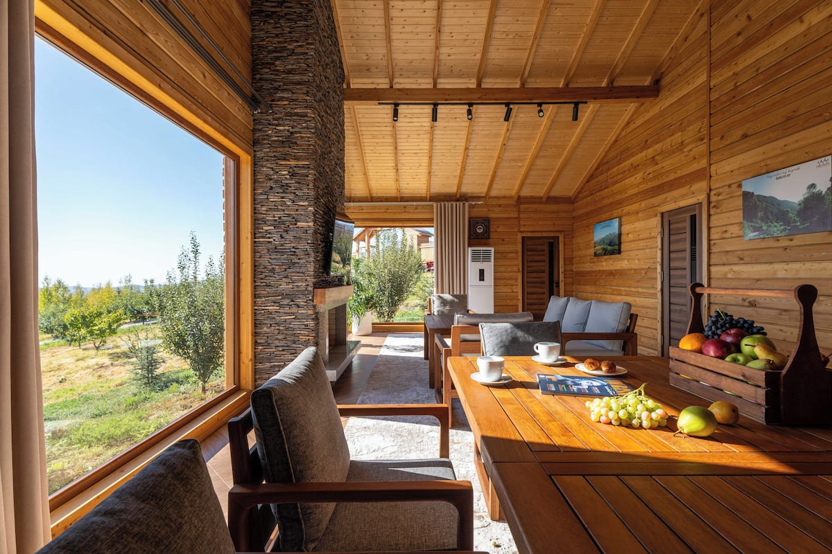 Une cabane en bois avec un coin repas, un pilier en pierre et une vue sur l’extérieur.