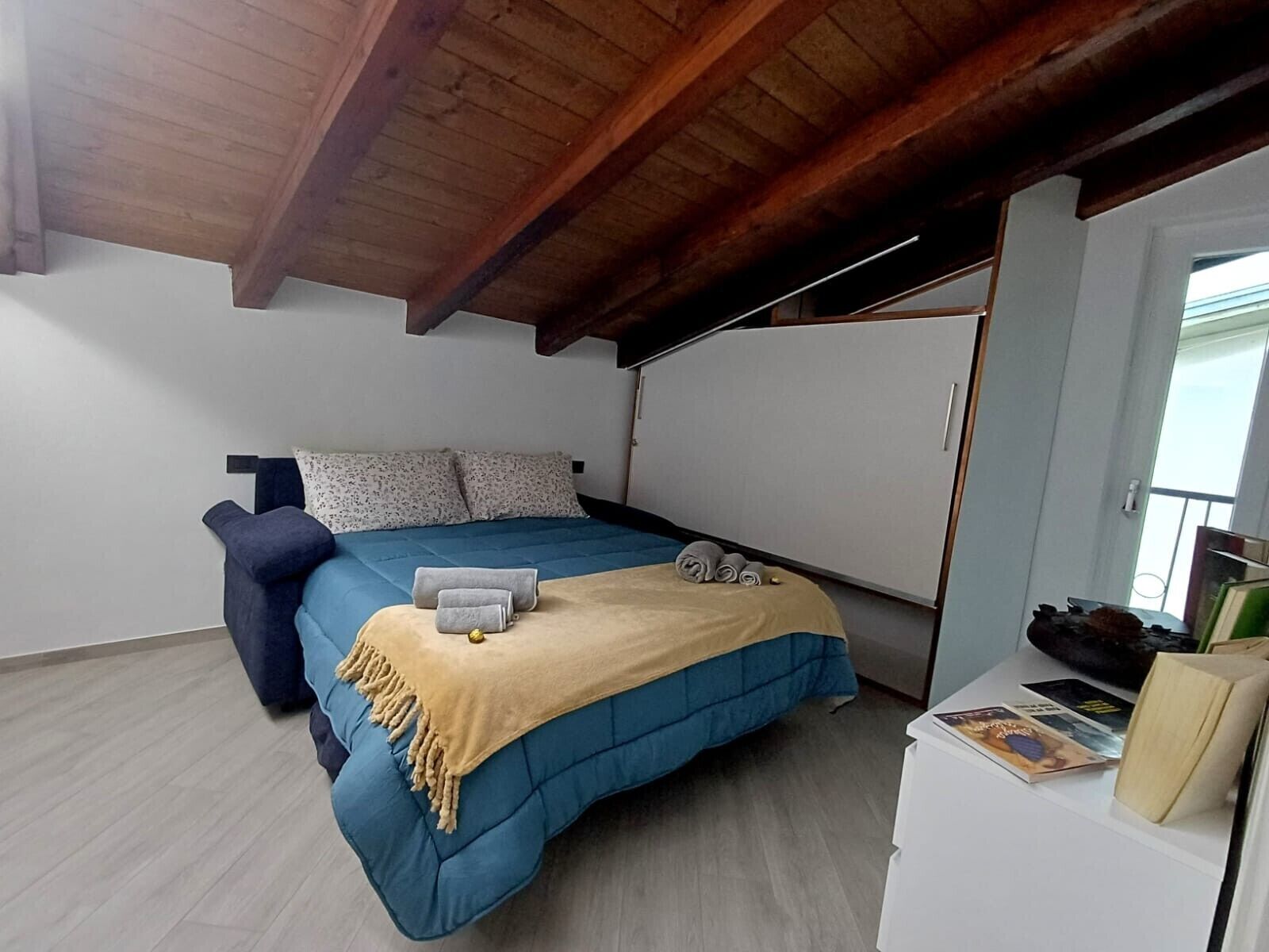 Ein Schlafzimmer mit einem Bett, einem Sessel, einem Kleiderschrank und einem kleinen Tisch mit Büchern.