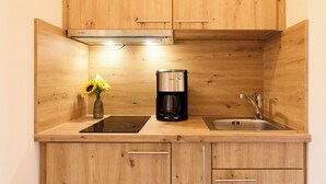 A kitchen with wooden cabinets, a coffee maker, a sink, and a vase with flowers.
